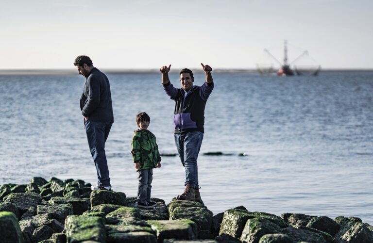 Fluechtlinge aus Syrien, Afghanistan und dem Irak beginnen ihr Leben auf der Nordseeinsel Borkum - die meisten warten auf die Ankunft ihrer Familien. Hier: Fawzi Nasser Obaid, sein Sohn Ibrahim und Hisham Al Shuraa aus dem Irak beobachten eine Sandbank mit Robben auf der Nordseeinsel Borkum, eine Woche nach ihrer Ankunft..Aufnahmen am 26.10.2015. Migrants from Syria, Afhanistan and Iraq are starting their new life on the german island Borkum, located in the Atlantic Sea, close to the Netherlands. (KEYSTONE/LAIF/Dominik Butzmann)