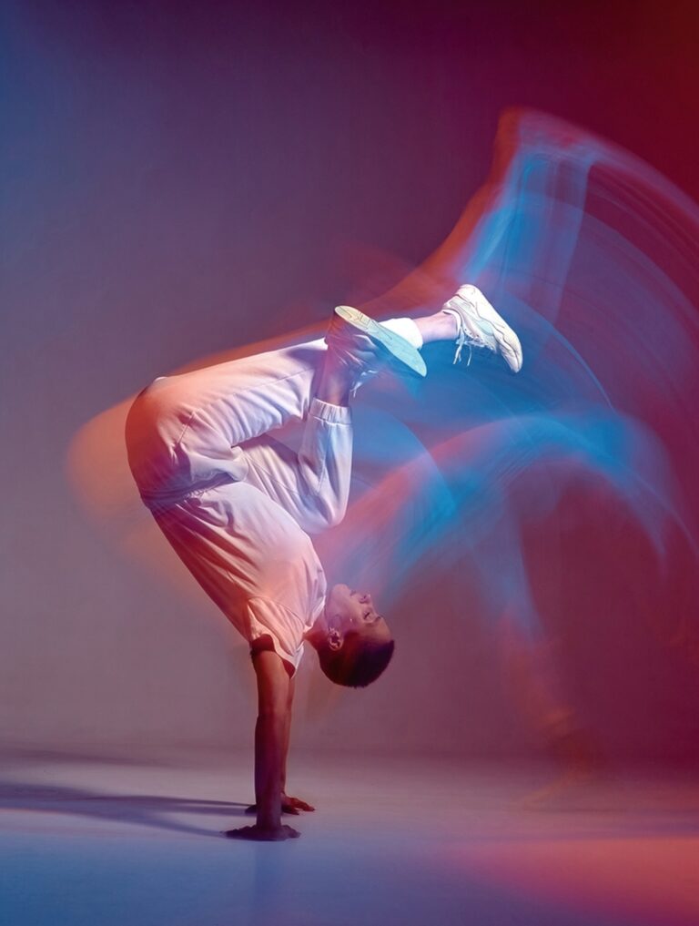 Young girl dancing contemporary dance in neon studio light. Acrobatic dancer. Breakdance school ad. Long exposure