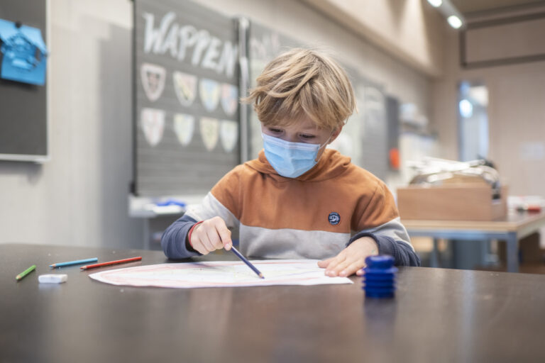 Ein Schueler traegt eine Kinder-Maske, um sich und andere gegen eine Uebertragung des Coronavirus zu schuetzen, in einem Schulzimmer der Schule Pfingstweid in Zuerich, aufgenommen am Dienstag, 11. Januar 2022. Um nach den Weihnachtsferien den Schulbetrieb möglichst sicher starten zu können, wurde die Maskentragpflicht in Zuerich und anderen Kantonen ab dem 3. Januar 2022 auch auf Schuelerinnen und Schueler der 1. bis 3. Primarschulklassen ausgeweitet. (KEYSTONE/Ennio Leanza)