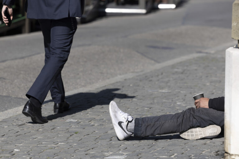 Un homme passe vers un mendiant qui fait la manche sur la place du Bourg-de-Fourg, ce vendredi 25 mars 2022 a Geneve. (KEYSTONE/Salvatore Di Nolfi)