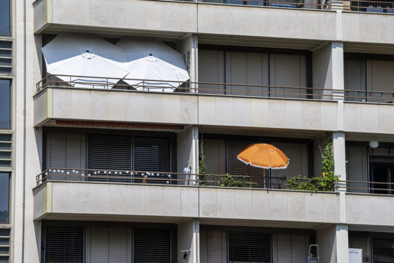 Une facade d?un immeuble est photographie avec des parasols de jardin et des stores metallique qui sont fermes afin d?assurer au mieux la fraicheur dans les appartements en cette periode de canicule, ce mercredi 20 juillet 2022 a Geneve. (KEYSTONE/Martial Trezzini)