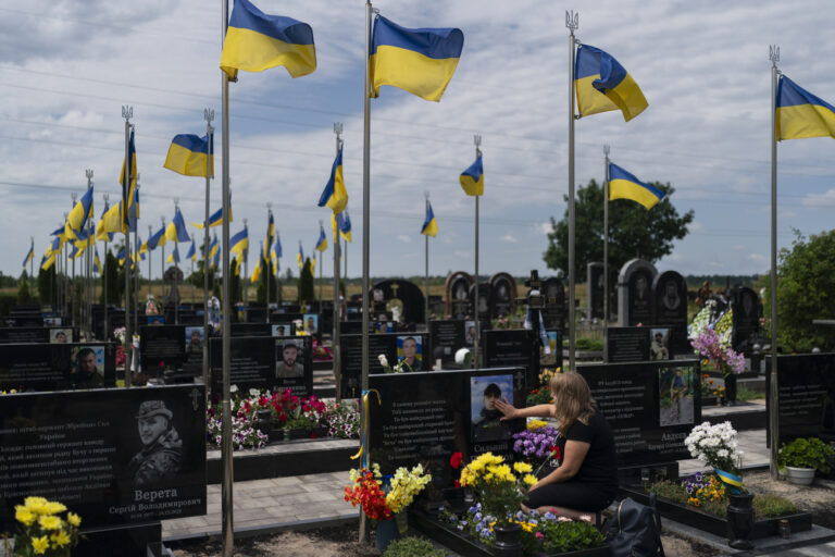 Svitlana, who wished to be identified by her first name only, touches the photo of her son, Vladyslav Cherniakov, at his grave in Bucha, Ukraine, Tuesday, July 18, 2023. The Ukrainian soldier was killed near Avdiivka in Ukraine's Donetsk region. (AP Photo/Jae C. Hong)