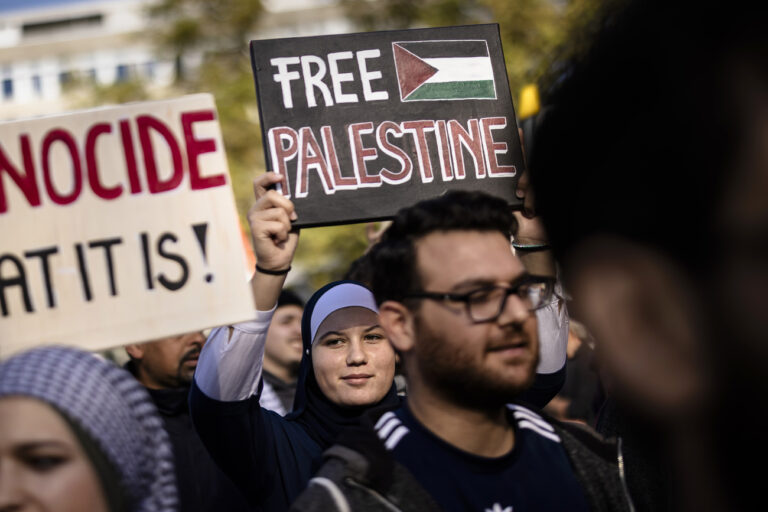 Protesters hold Palestinian flags and placards reading 