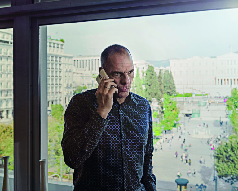 YANINS VAROUFAKIS  talking on the phone in his office that looks Syntagma Square