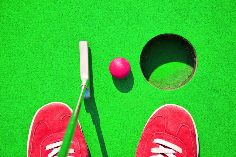 Close-up of miniature golf hole with bat and ball